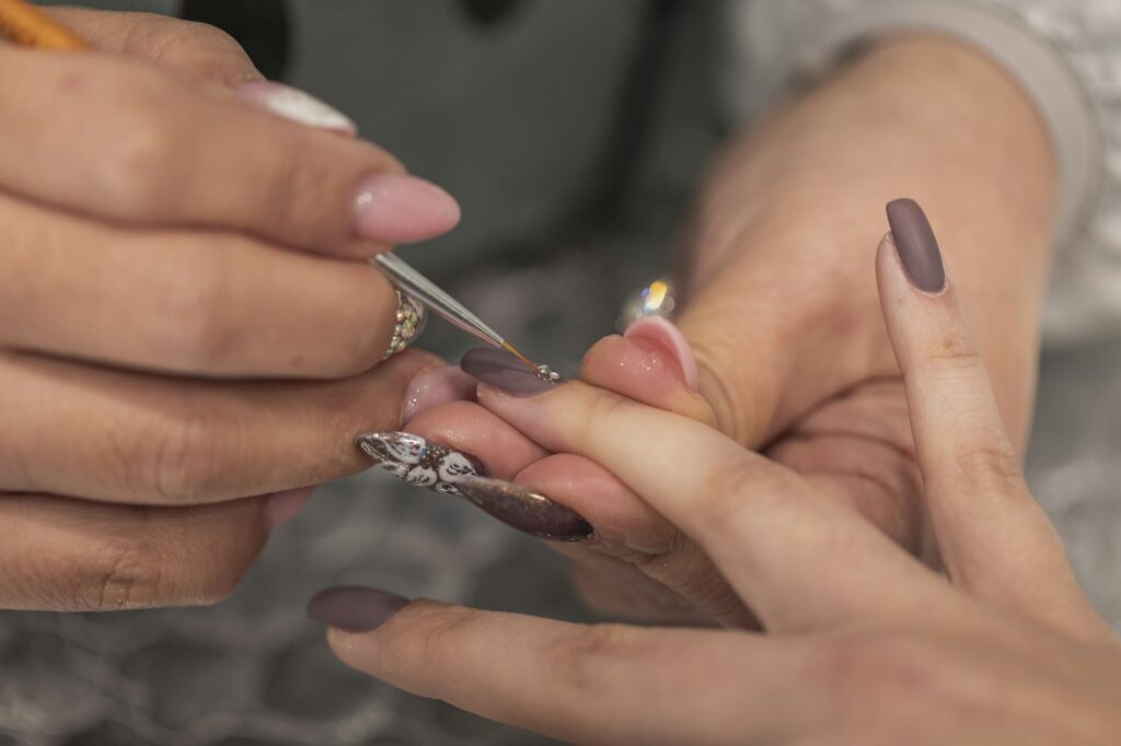 Nail stylist decorating customer's fingernails